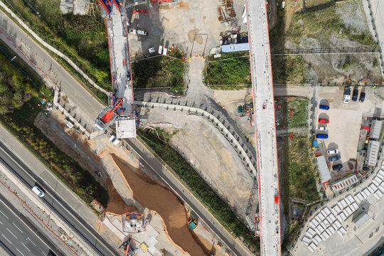 Aerial view of high speed rail construction site with concrete bridge pillars and heavy machinery in the United Kingdom.