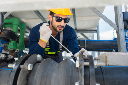 Worker man maintaining industrial plumbing and machinery equipment, engineer repairing water treatment facility pipes and valves, Technician using wrench to tighten bolts on pipeline and valve system