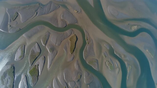 Stunning aerial view of river meandering through mudflats and channels, creating abstract natural patterns in an estuary