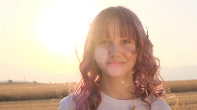 Cute preteen girl with curly red hair and brown eyes smiles peacefully outdoors in autumn, with straw in her hair after playing in a pile of straw, enjoying life, carefree childhood, outdoor childhood