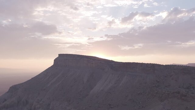 Sunlit clouds behind a wide desert mesa