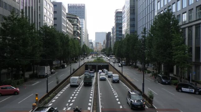 Chiyoda, Tokyo Japan - October 4, 2026: Traffic entering an underpass tunnel on a straight urban avenue with office buildings (tokyo-underpass-entry-20261004)