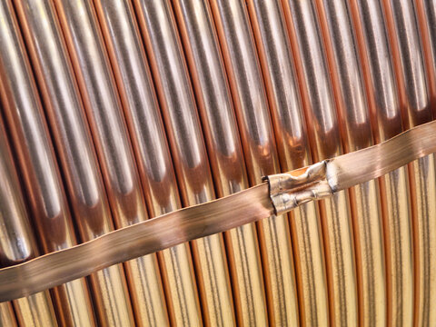 Metal tubes made of copper arranged in a row, featuring varying colors and textures