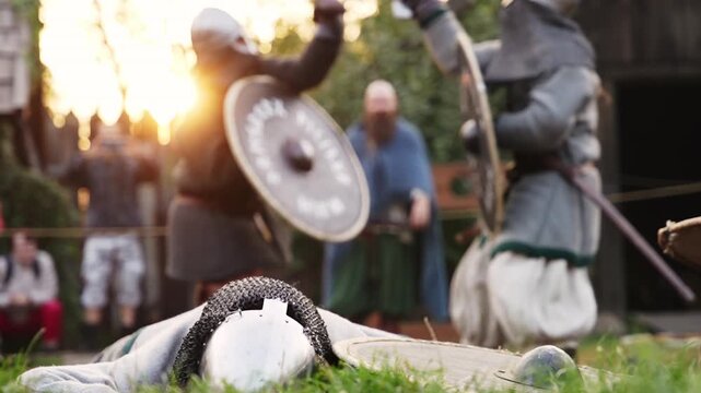Two Viking warriors fighting with swords and shields while fallen warrior lies in foreground.