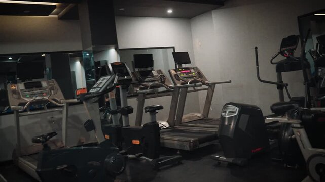Interior video shot showcasing gym cardio workout area with modern treadmills, ellipticals, and stationary bikes in a health club.