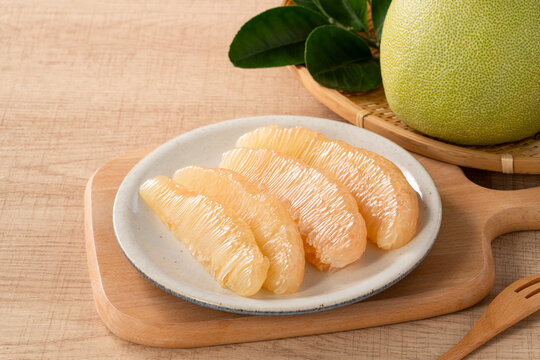 Fresh pomelo fruit with leaf on wooden table background.
