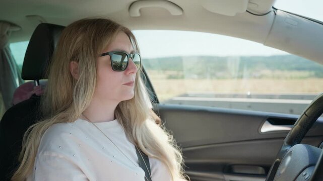 Woman driving car on sunny road trip slow motion wearing sunglasses 35 years old