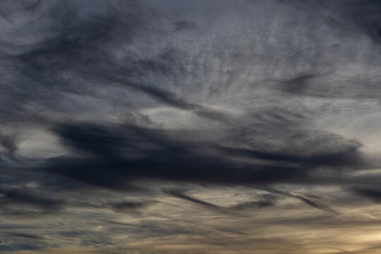 Swirling dark cloud layers catching subtle twilight glow across a moody sky