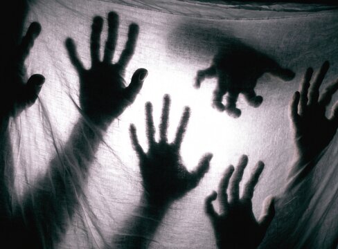 Creepy silhouette of ghost hands scratching transparent plastic film horror art