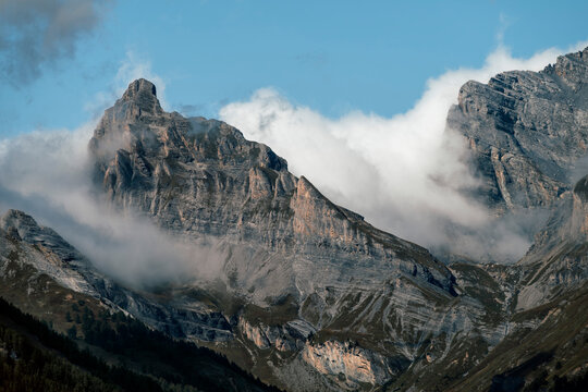 Dramatic rugged mountain peaks emerging through dense clouds in Valais, Switzerland.