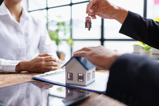 Real estate agent handing over house keys to a client, symbolizing home ownership, property transfer, and successful closing of a contract for a new home purchase or rental agreement