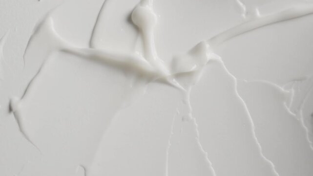 Cosmetic cream smearing with spatula on white background. Macro shot of white beauty product texture and skincare swatch