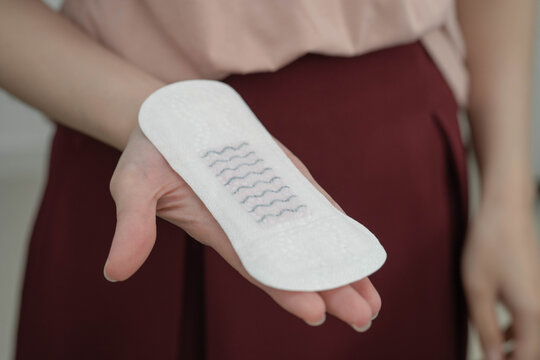 Asian woman holding sanitary napkin pad for hygiene menstrual period cycle protection.