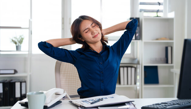 Asian businesswoman with shoulder pain from sitting at work all day. Massage for overworked shoulders. Health and office syndrome concept.