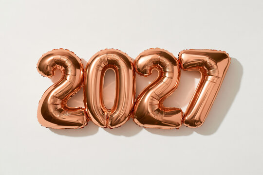 Balloons shaped like 2027 in a shiny rose gold color on a plain background