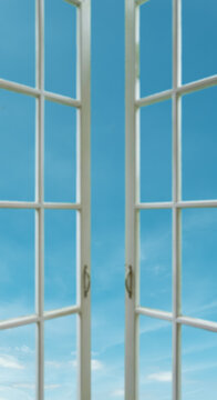 Sunny day view of blue sky through an open white wooden window
