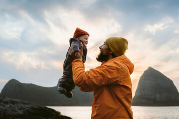 Naklejka na ściany i meble Baby and father enjoying time together family travel dad lifting infant child outdoor, autumn vacations in Norway tour with kid candid emotions happy moment fatherhood childhood Fathers day holiday