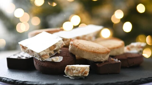 Close-up video of traditional Spanish turrones and polvorones rotating on a plate. Assorted festive sweets typical of Christmas in Spain presented as a seasonal holiday dessert.