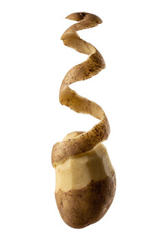 Spiral potato peel curling around a half-peeled potato on a black background