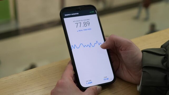 Person monitors real-time crude oil prices on a smartphone, highlighting energy market volatility, commodity trading and changing global fuel costs.