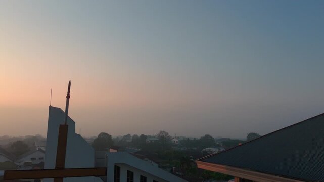 Aerial view of a church roof with a cross and pigeons perched at sunrise in Malang, East Java, Indonesia.