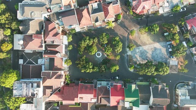 Aerial view of a residential neighborhood with red-tiled rooftops and a small central park in Malang, East Java, Indonesia.