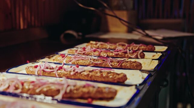 A row of plated Georgian kebabs on lavash waiting under the warm light of the restaurant pass.