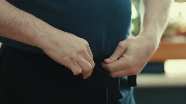 Macro Shot of Male Chef Tying Black Kitchen Apron Strings Around Waist