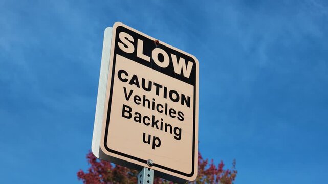 Slow Caution Vehicles Backing Up Traffic Warning Sign with Autumn Trees