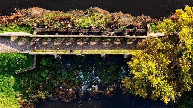Aerial view of the historic stone bridge and dam at Pakruojis Manor surrounded by autumn trees in Pakruojis, Siauliu apskritis, Lithuania.