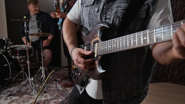 Midsection shot of male guitarist plugging audio jack into electric guitar and playing with band. Ideal for music tutorials, audio equipment advertising, band promotion campaigns