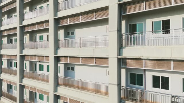 Aerial view of a modern multi-story apartment building with balconies and louvered window shades in Malang, East Java, Indonesia.