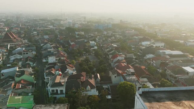 Aerial view of residential rooftops and urban landscape during a hazy morning in Malang, East Java, Indonesia.