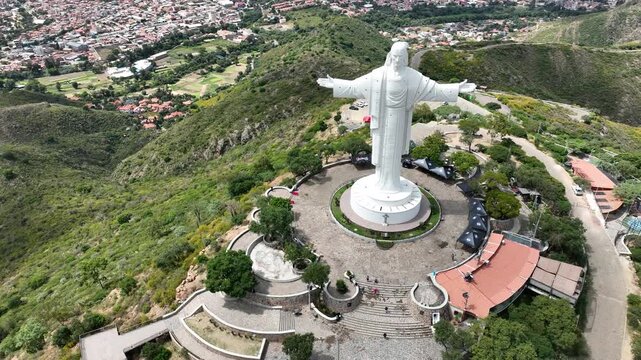 Aerial view of the Christ of the Concord Monument standing on a hilltop surrounded by lush greenery and paved plazas in Cochabamba, Departamento de Cocha, Bolivia.