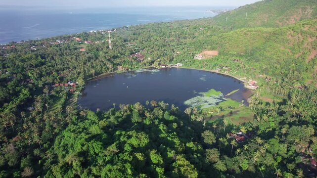 Aerial view of Danau Yeh Malet surrounded by lush tropical vegetation and hills in Kecamatan Manggis, Bali, Indonesia.
