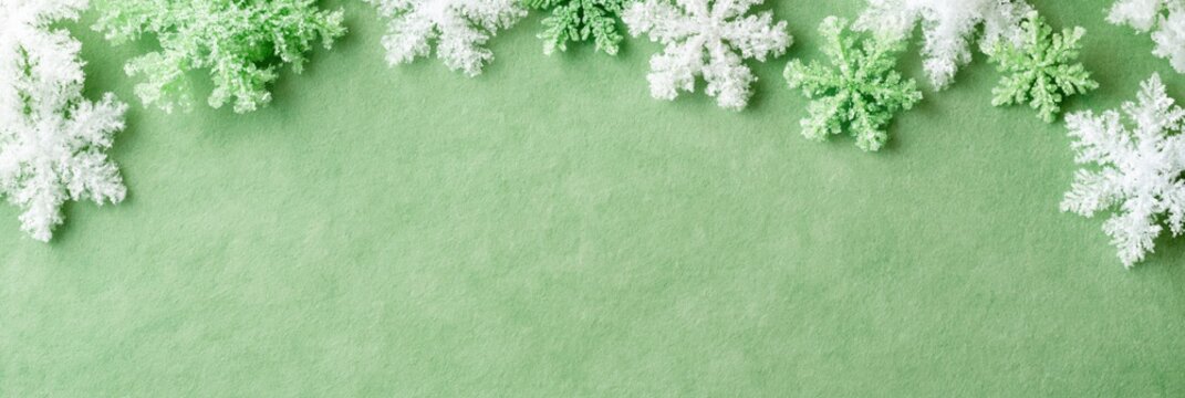 Panoramic green snowflake header background for christmas and winter holiday banner or website hero with pastel textured paper space