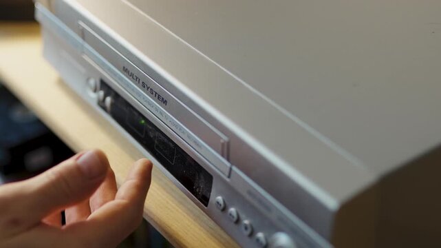 Close up of hand inserting tape into retro video recorder