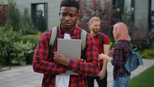 Group of aggressive students bullying African American student guy unhappy feeling shame in city ethnic man male upset with mockery bully multiracial classmates laughing discriminate at university