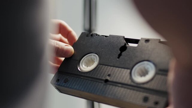 Close up of male hands holding and inspecting retro video tape