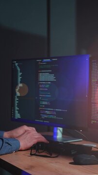 Man types code at computer in dark room