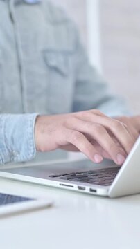 Close up of young man using laptop in modern office