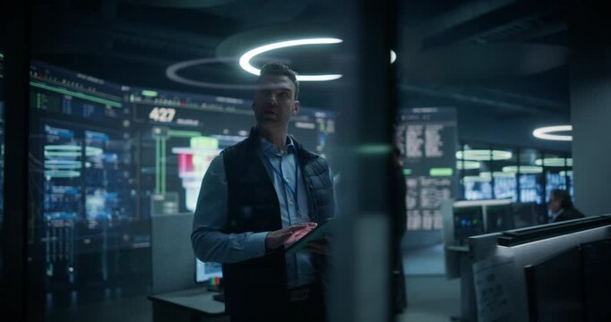Nuclear Energy Powerplant Monitoring Control Room. Technician Checks a Tablet as Teams Oversee Reactor Diagrams, Code and Output, Ensuring Stable Work  Through Quantum Computer Science and Technology