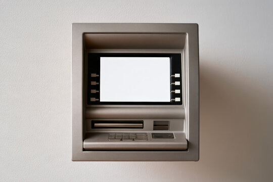 Straight on close view of a clean modern ATM mounted on a light wall. Cash machine, banking technology, financial access, public service.