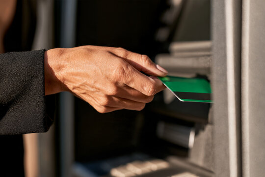 Close up of a businesswoman using a green card at an ATM. Card payment, personal banking, cash access, financial service.