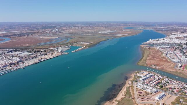 Aerial drone view flying forward over the guadiana river, which forms the natural border between ayamonte in andalusia, spain, and vila real de santo antonio in the algarve region of portugal