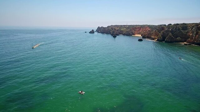 Stunning aerial perspective showing kayakers and tourist boats navigating the beautiful emerald waters near the dramatic cliffs and grottos of ponta da piedade in lagos, algarve, portugal