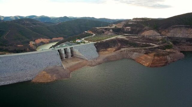 Magnificent aerial perspective of the odelouca dam, showcasing the large reservoir and surrounding hilly landscape in the algarve region of portugal, a key structure for water management