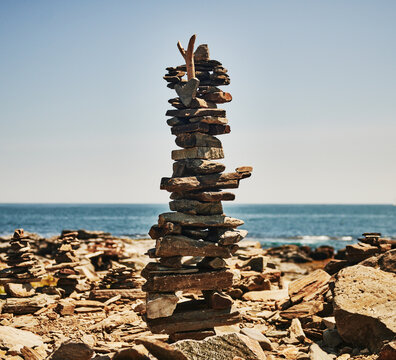 balanced stone sculpture, aka rock stack or cairn, built on a larger coastal rock under a clear blue sky, Peaks Island, Maine, New England 