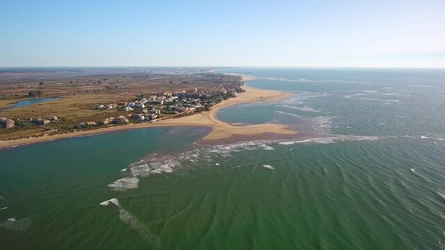 Scenic aerial view flying over the beautiful coastline of isla canela beach in ayamonte, huelva, showing the turquoise atlantic ocean waters meeting the sandy shores of andalusia, spain