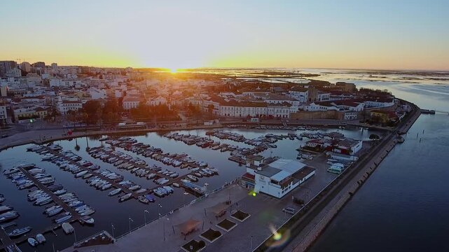 Aerial view showing faro city center and its scenic marina filled with yachts and boats, reflecting the warm glow of the sun setting over the ria formosa lagoon in algarve, portugal
